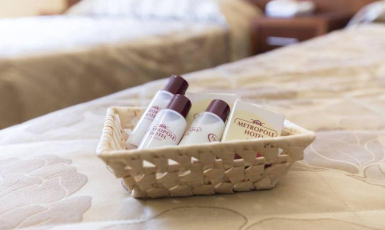 Cestino di cortesia con prodotti da bagno su letto elegante in hotel.