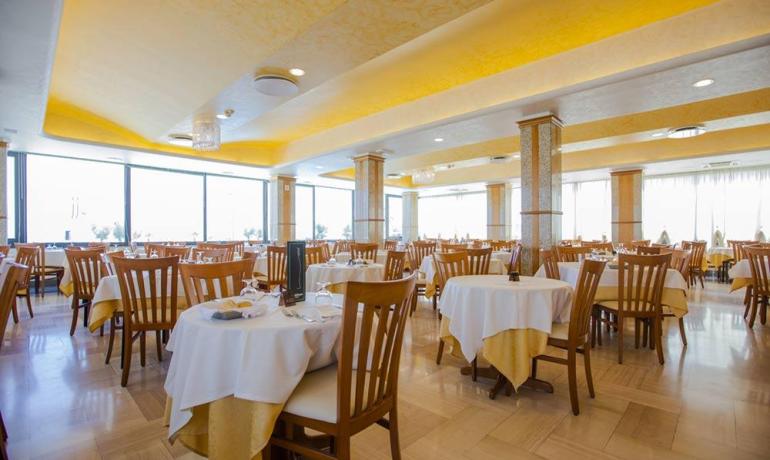 Ristorante elegante, tavoli apparecchiati, luce calda, atmosfera accogliente e rilassante.